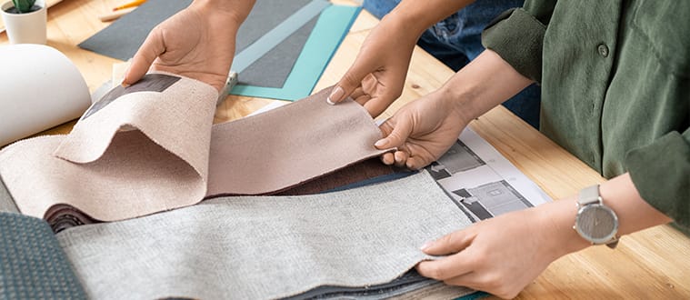 Deux personnes réalisant du sourcing matières de tissus sur un bureau pour la fabrication de vêtements