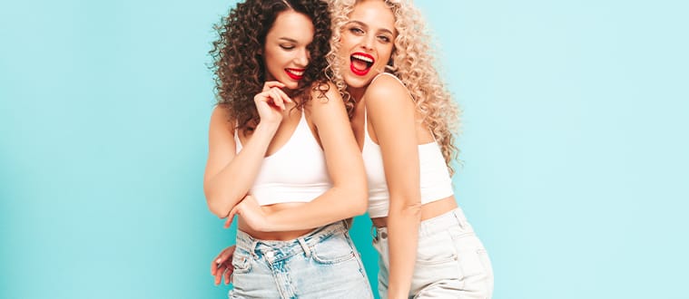 Deux femmes souriantes en jean et crop top blanc à bretelles